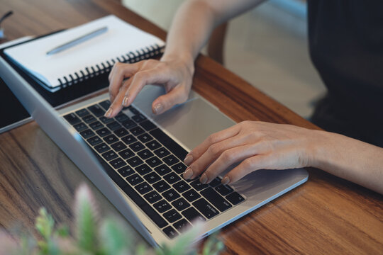 Close up of woman typing on laptop  at wooden desk, remote work, online business concept.