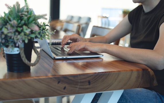 Woman working on laptop,  focusing on task on desk in cafe, modern workspace, representing online business and remote work concept