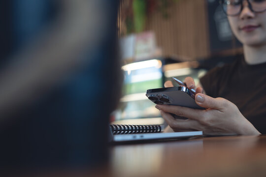 Close up of woman using smartphone at desk with notebook, modern remote work and digital lifestyle concept.