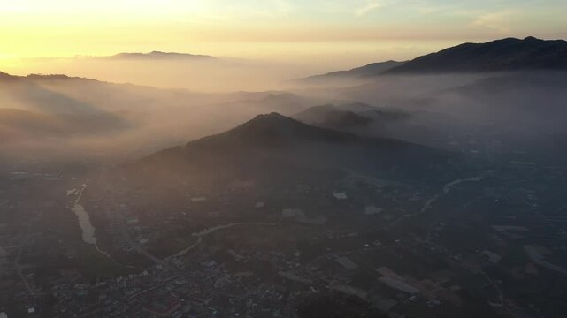 Aerial drone view of D&rsquo;Ran Pass and D&rsquo;Ran in Lam Dong, Vietnam, glowing in the first light of sunrise, with winding mountain roads, green valleys and misty highlands.