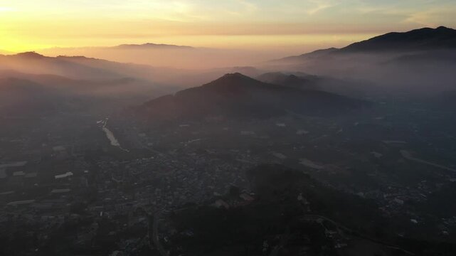 Aerial drone view of D&rsquo;Ran Pass and D&rsquo;Ran in Lam Dong, Vietnam, glowing in the first light of sunrise, with winding mountain roads, green valleys and misty highlands.