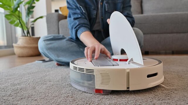 Woman cleaning and launching vacuum cleaner. Smart home concept