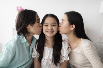 Obraz premium Smiling Happy Asian Woman Kissing Young Girl On Cheek While Featuring Another Woman Drifting Close At Home, Showcasing Affection And Love Within Their Family Atmosphere.