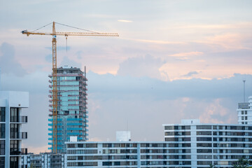 Tower crane heavy machinery operating at the high-rise skyscraper building construction site above the residential apartment architecture. © AncientAftertone
