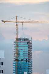 Tower crane heavy machinery lifting equipment operating at the glass facade skyscraper building construction site during the development. © AncientAftertone