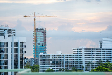 Tower crane equipment operating at the skyscraper building construction site behind the city residential apartment building architecture. © AncientAftertone