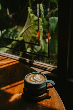 Aesthetic cafe scene with an artisanal cup of coffee, rich moody tones, and striking shadows from the morning sun