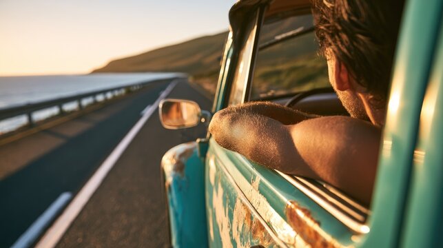 A man driving a vintage van along a scenic coastal road during sunset.
