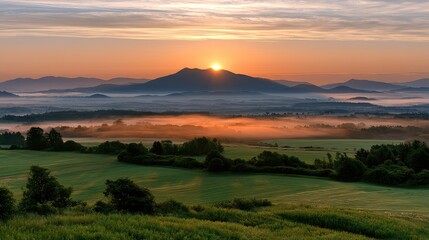 Fototapeta premium Stunning Sunrise Over Misty Mountains in Lush Green Landscape