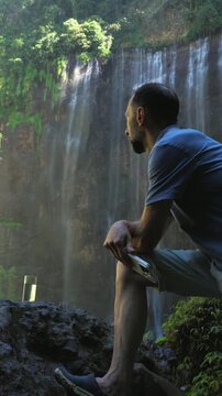 Pensive male traveler watching tumpak sewu waterfall in indonesia