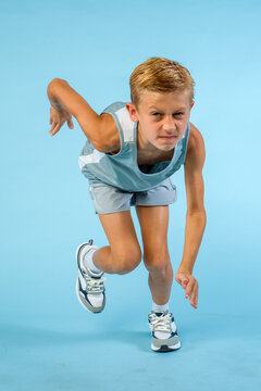 Action shot of a running boy mid stride, wearing a track team uniform and running shoes 
