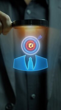 Close-up vertical shot of hand holding magnifying glass inspecting businessman avatar with target bullseye head. Executive talent recruitment search, candidate headhunting, and hiring concept.