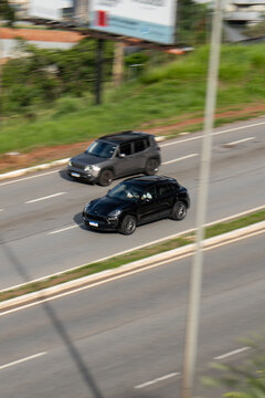 High-Angle Panning Shot of a Black Porsche Macan and Grey Jeep Renegade Driving on a Highway