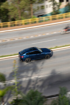 High-Angle Motion Shot of a Blue BMW X4 Driving on an Urban Highway