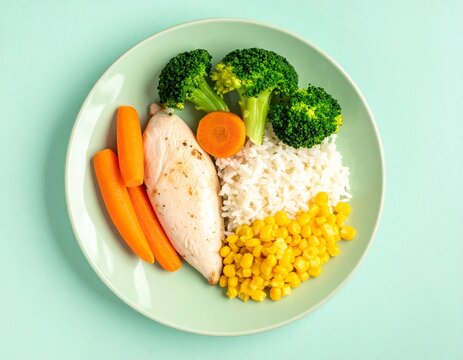 Healthy kid lunch plate with baked chicken breast, rice, broccoli and corn