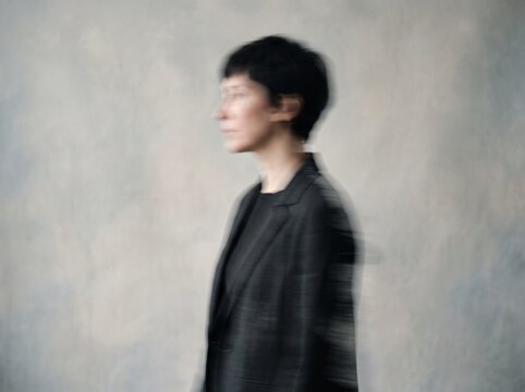 Anonymous Adult in Soft-Focus Side Profile Against Neutral Wall