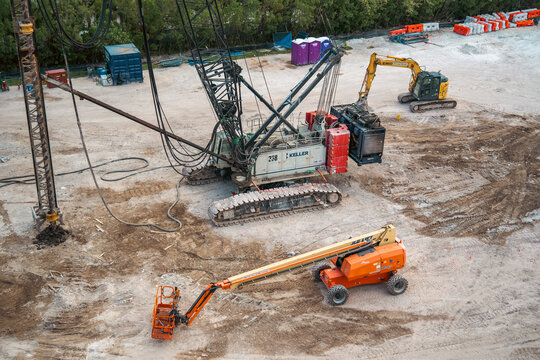 Keller crawler crane and JLG lift heavy machinery equipment parked on the ground at the commercial building foundation construction site. Hollywood, Florida, USA - August 21, 2026