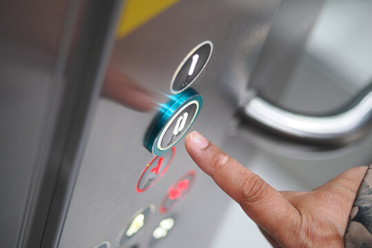 Person presses elevator button to go to a floor