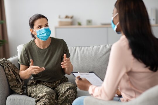 Worried Female Soldier Of Caucasian Ethnicity Discussing Mental Health Issues With Therapist In An Office Setting, Engaging In A Supportive Conversation To Address Emotional Wellbeing And Care.