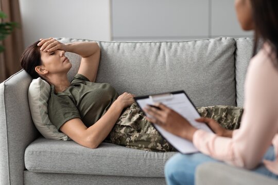 Worried Caucasian Female Patient Laying On Couch During Consultation With Therapist In Mental Health Office. Discussing Emotional Wellbeing And Mental Health Challenges In Safe Environment.