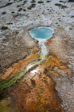 Turquoise water in geothermal hot springs in West Thumb Geyser Basin, sunny day traveling in Yellowstone National Park for summer vacation
