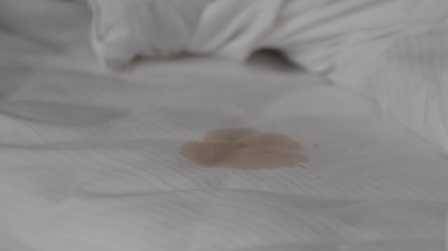 Stain on a white bed sheet in a bedroom setting