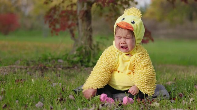 Crying Baby in Yellow Duck Halloween Costume on Autumn Lawn