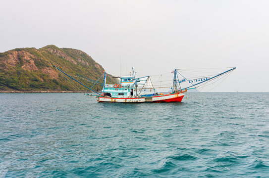 Commercial wooden squid fishing boat with outriggers anchored near Koh Kham Island. Traditional Thai squid fishing boat with extended riggers floating near Koh Kham in Sattahip, Chon Buri, Thailand.