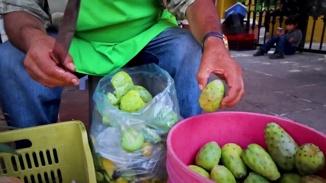 Man Peeling Fresh Cactus Pear Fruit By Hand At Outdoor Mexican Market Stall