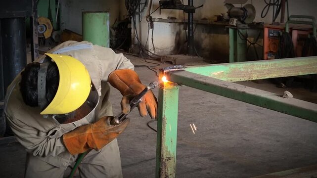 Workers wearing safety suits and gloves use high-temperature gas torches to cut the steel.