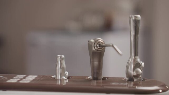 Close up of dental handpieces and burs on sterilization tray showing various sizes. metal instruments are arranged in their holders with soft lighting highlighting shiny surfaces against out