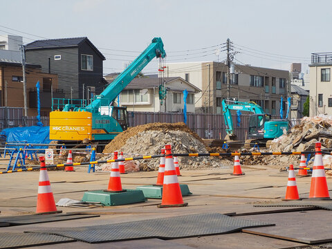TOKYO, JAPAN - April 14, 2026: A crane and an excavator truck on a construction site surrounded by low-rise buildings in Jingumae.