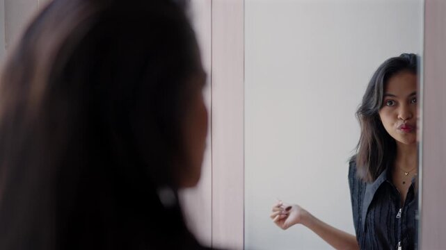 Young asian woman applying blush makeup in mirror