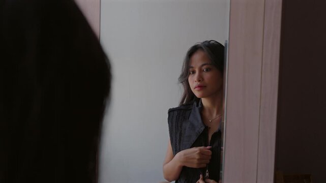 Young woman getting ready looking in the mirror
