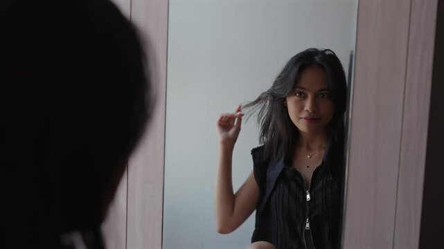 Beautiful asian woman looking at her reflection in the mirror