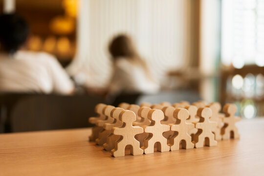 Human resources and teamwork concept with crowd of natural wooden people figures standing together on table in cafe for corporate workforce management, recruitment and community unity.