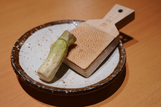 Fresh raw wasabi root with a traditional wasabi grater on wooden table 
