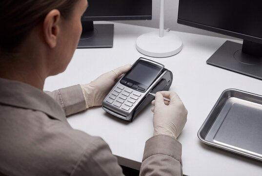 Technician wearing latex gloves operates a digital payment terminal on a clean transparent background office desk surface.