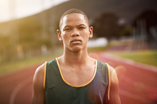 Portrait, athlete and teenager on track for fitness, exercise and practice for school challenge. Serious, boy or student runner at stadium for marathon training, sprint and competition at sport event