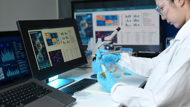 Asian female scientist examines a chemical flask and takes notes in a futuristic laboratory. She analyzes DNA sequencing data