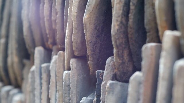 Close-up slide shot of stacked old clay roof tiles showing rough texture, weathered edges, and stacked parallel lines for construction.