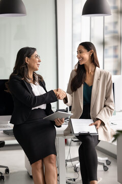 Diverse businesswomen handshaking in office, represents corporate agreement, closing deal, successful negotiation between two colleagues or partners. Professional collaboration, business partnership