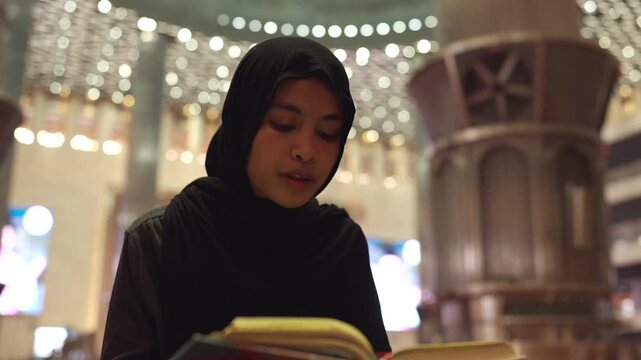 Devout muslim woman reading the quran inside a mosque