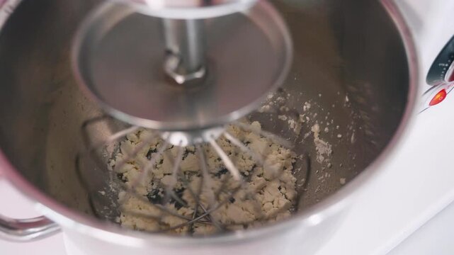 Close-up video of albumin being mixed with water in a stand mixer during the preparation of French macarons. Baking ingredients and pastry making process in a kitchen.