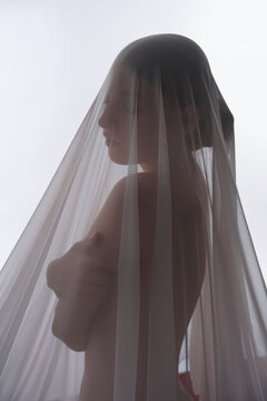 Ethereal portrait of woman in profile hidden behind translucent veil