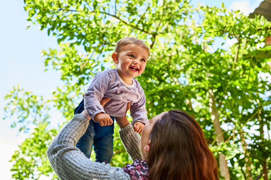 Happy, mother and lift baby outdoor with love, bonding together or support for childhood development. Woman, smile and holding daughter in air with family connection, care and parent play with kid.