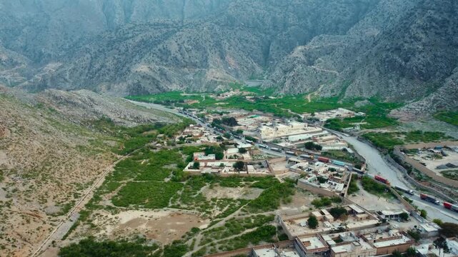 Aerial view of Landi Kotal in Khyber District, Pakistan, showing a rural settlement surrounded by rugged mountains, a green valley, roads, and cargo trucks.
Drone footage of rugged mountains 