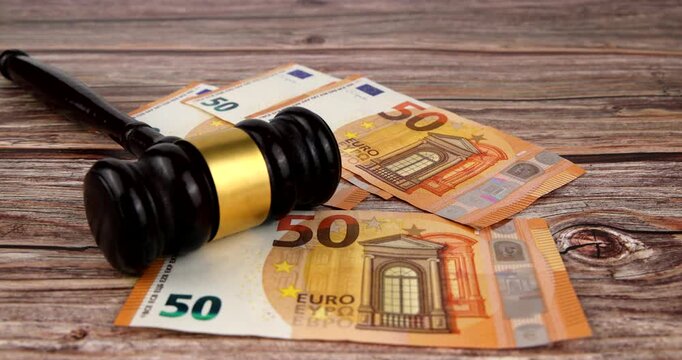 Wooden judge gavel on table with euro banknotes falling around in horizontal orientation representing European financial law and bribery