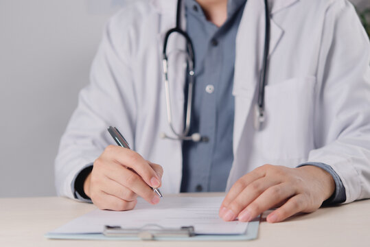 Healthcare professional writing medical notes on clipboard with stethoscope in clean office setting and copy space for healthcare content