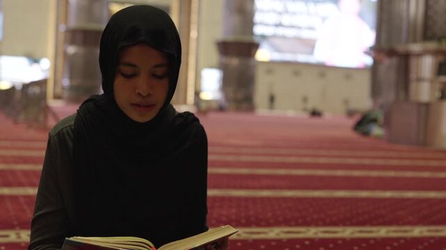 Muslim woman reading the quran praying in the mosque